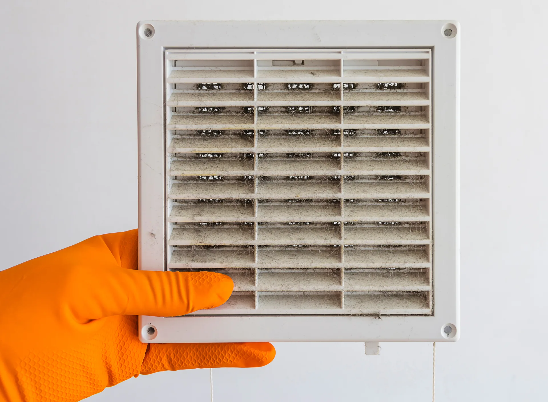 Gloved hand holding a dusty air vent cover, showing poor indoor air quality in an Avondale, AZ home Gloved hand holding a dusty air vent cover, showing poor indoor air quality in an Avondale, AZ home