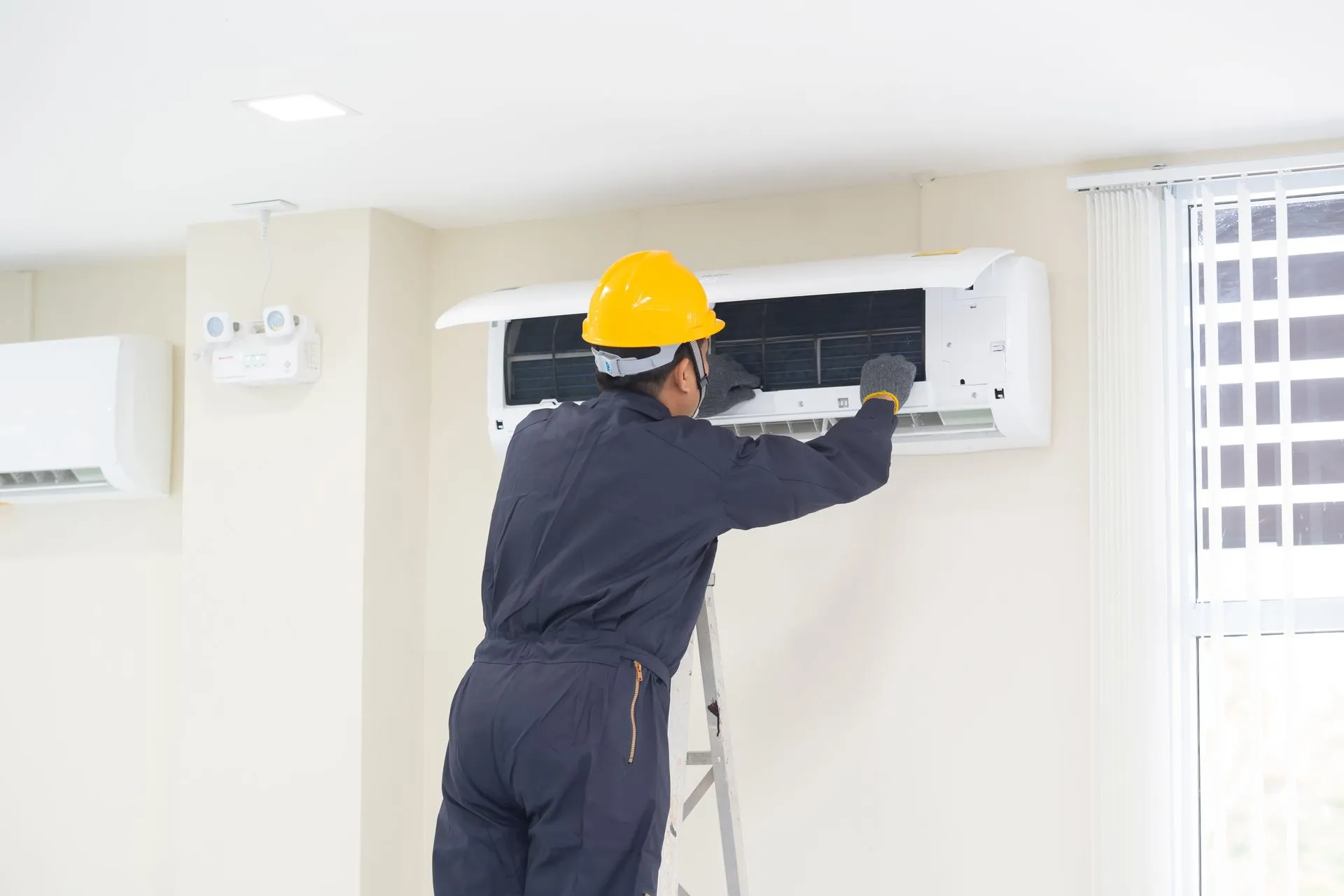 A man is working on an air conditioner inside a house in Youngtown, AZ A man is working on an air conditioner inside a house in Youngtown, AZ